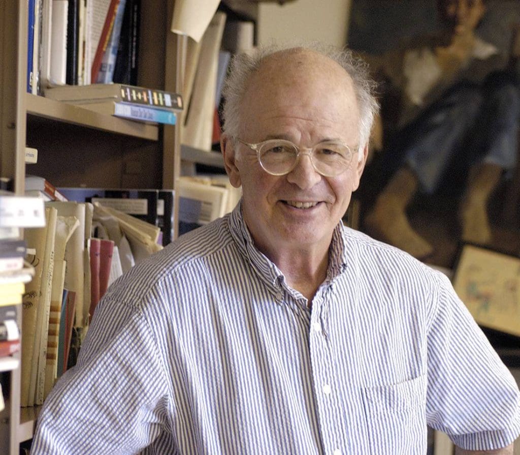 Author Stephen Dixon in his office, surrounded by books with a figurative painting behind him